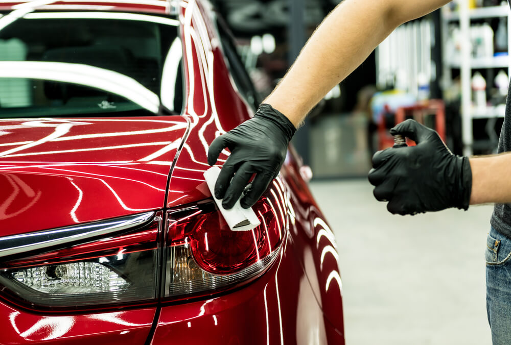 Car service worker applying nano coating on a car detail.