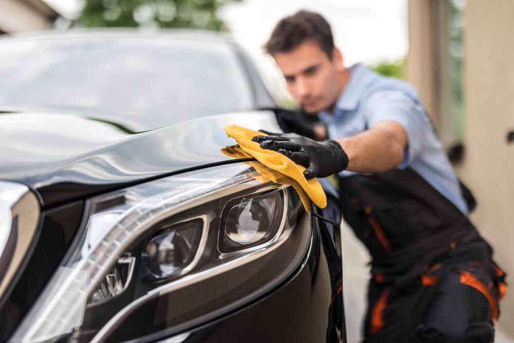 Car detailing - the man holds the microfiber in hand and polishes the car.