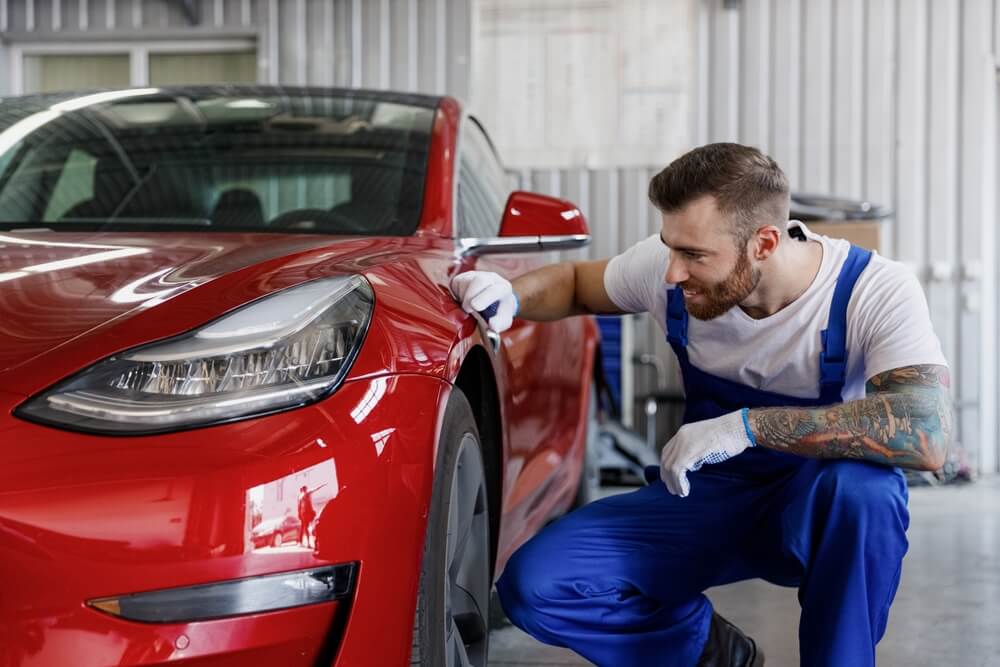 A car mechanic man checking car painting work.