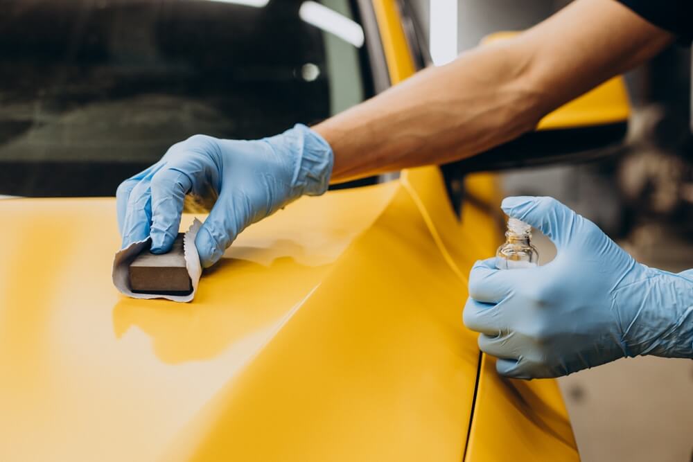 Man at car service doing car ceramic coating procedure.