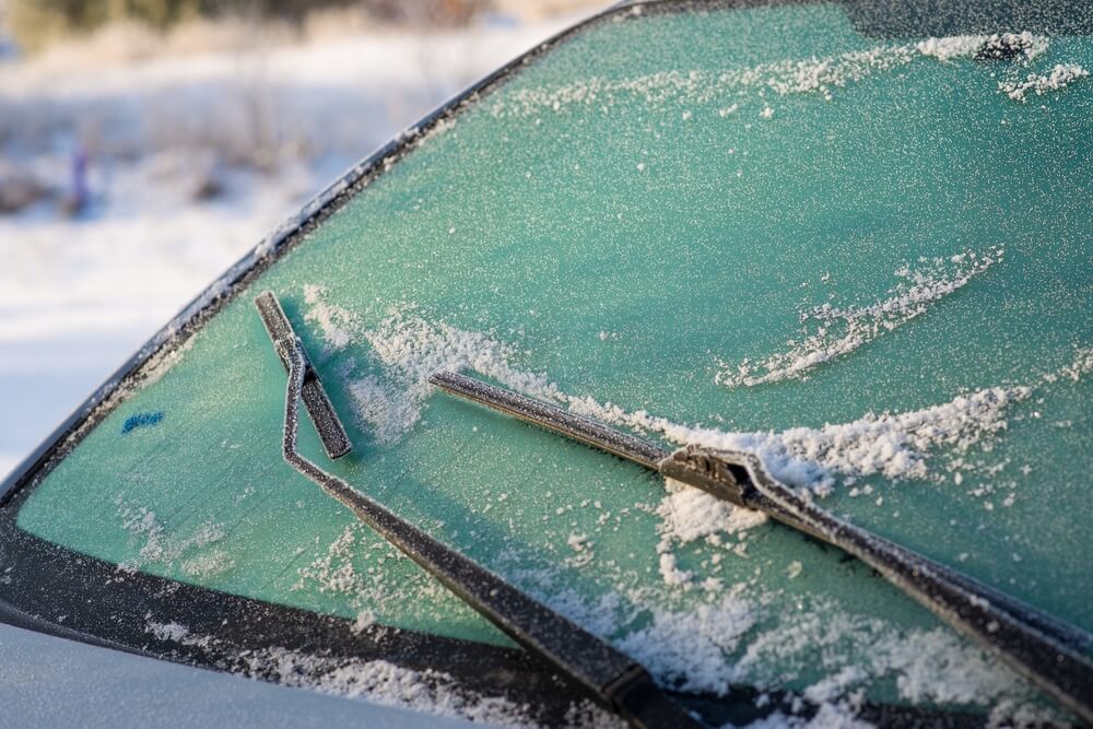 Snow-covered car windshield. Wipers and washers in frost.